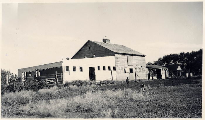 A train is stopped in a small town next to a train station and two elevators.