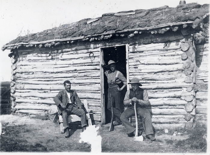 A train is stopped in a small town next to a train station and two elevators.