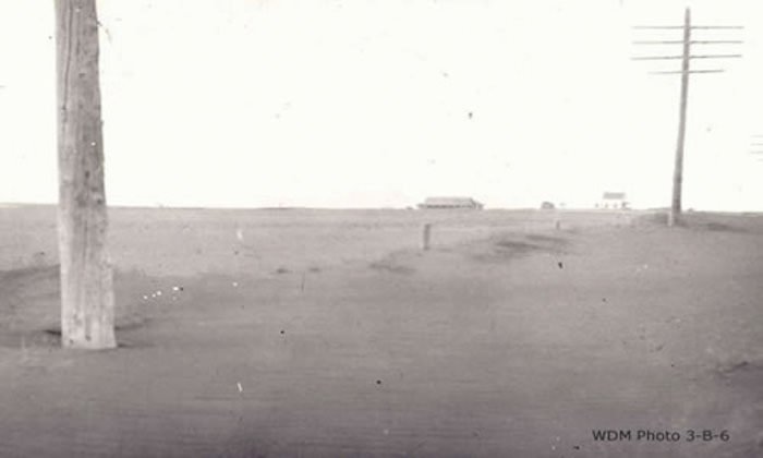 A train is stopped in a small town next to a train station and two elevators.