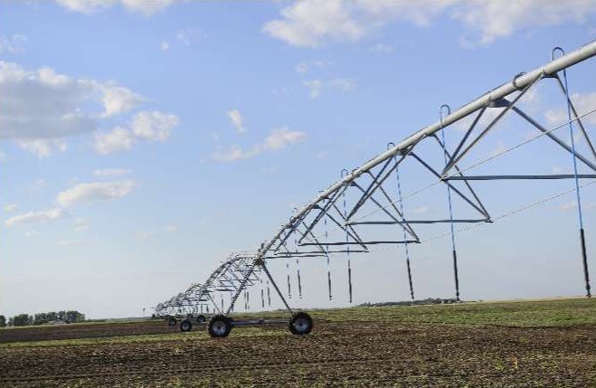 A train is stopped in a small town next to a train station and two elevators.
