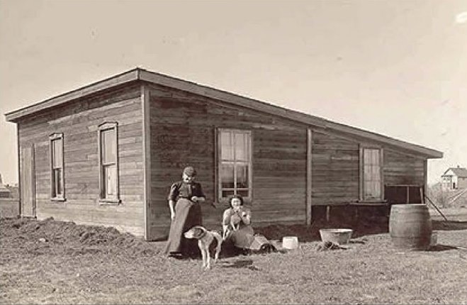 A train is stopped in a small town next to a train station and two elevators.
