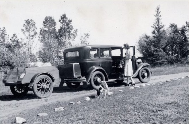 A train is stopped in a small town next to a train station and two elevators.