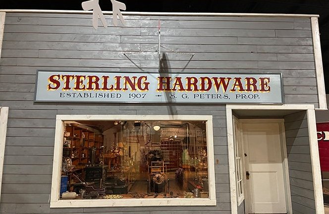 A mother and her three children are sitting down by their car to have supper in the field during harvest time.