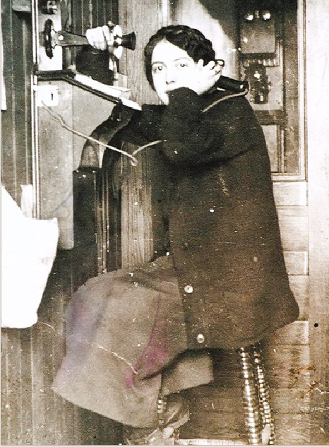 A group of men are working together to build a wooden grain elevator with piles of lumber nearby and a train in the background.