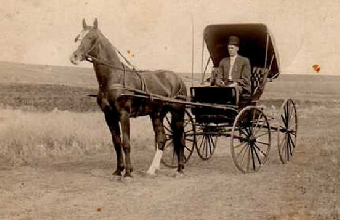 A train is stopped in a small town next to a train station and two elevators.