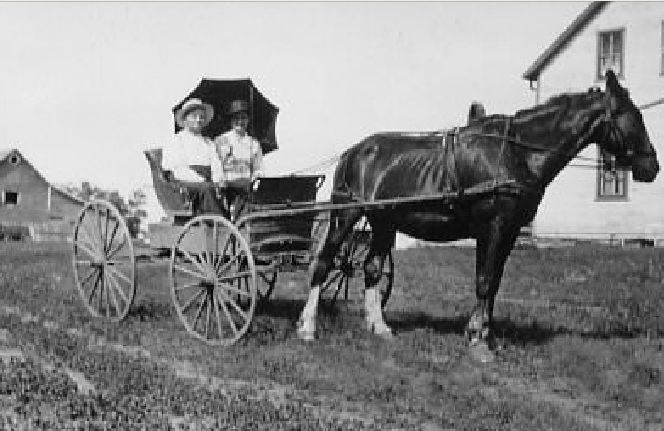 A train is stopped in a small town next to a train station and two elevators.