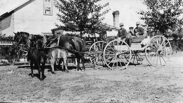A train is stopped in a small town next to a train station and two elevators.