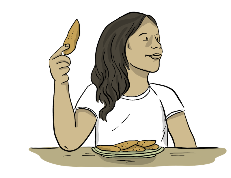 A girl is eating chicken with an apron on. 