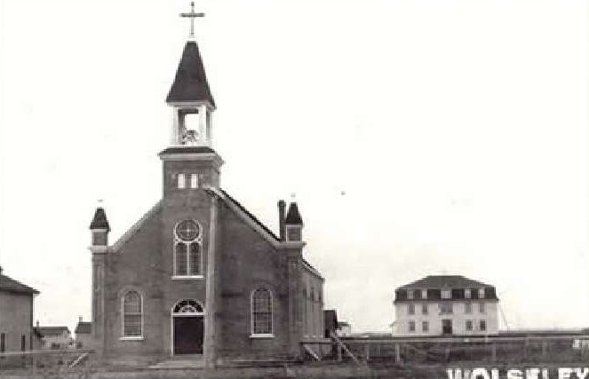 A church amongst a few other houses is being shown with the words 'Wolseley Sask' at the bottom of the photo.