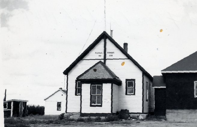 A wooden one-room school house has the words 'Floral School ' on it.