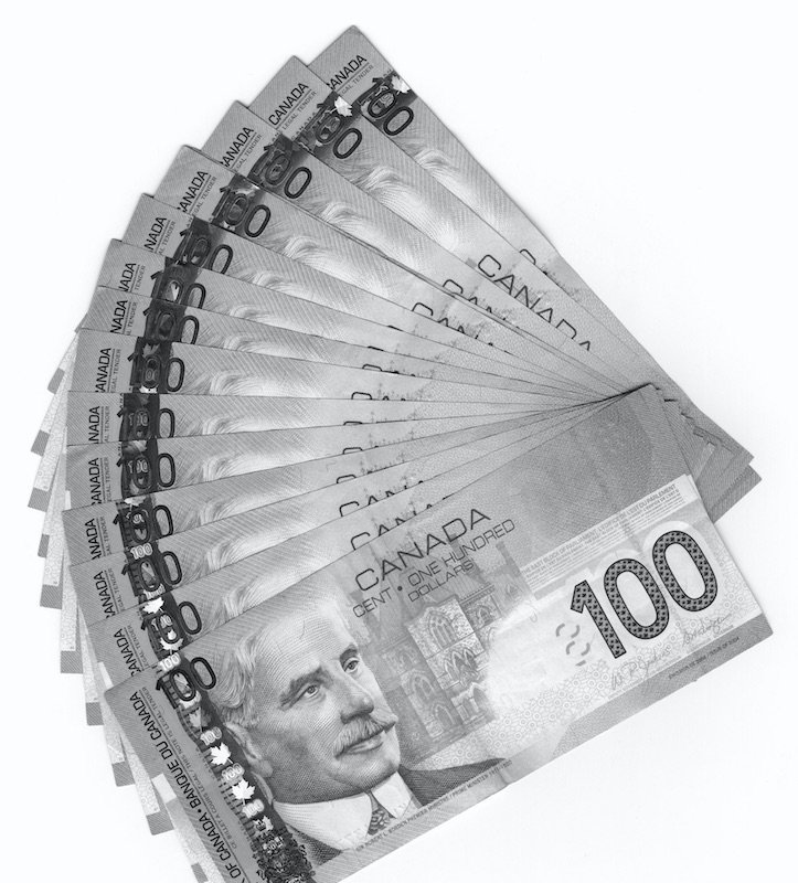 The photo shows a pile of Canadian one-hundred dollar bills