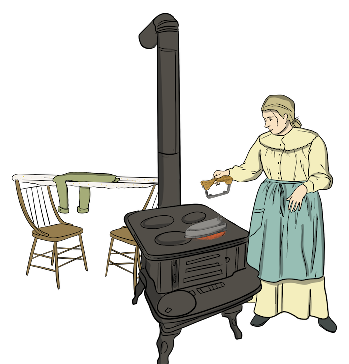 A woman is standing next to a stove and heating the iron on it. She clamps the handle onto the iron and then she can iron clothes that she has set out on a board. 