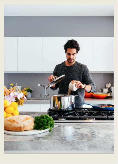 A Dad is busy cooking at a stove in the kitchen. 
