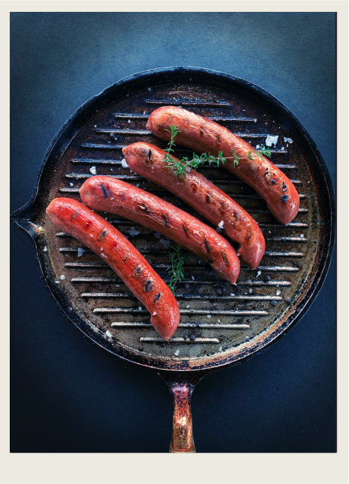 Photo caps-02 A frying pan with sausage is shown.