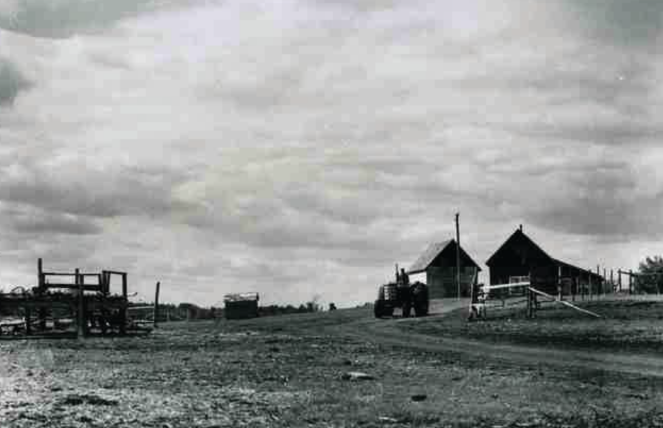 A train is stopped in a small town next to a train station and two elevators.