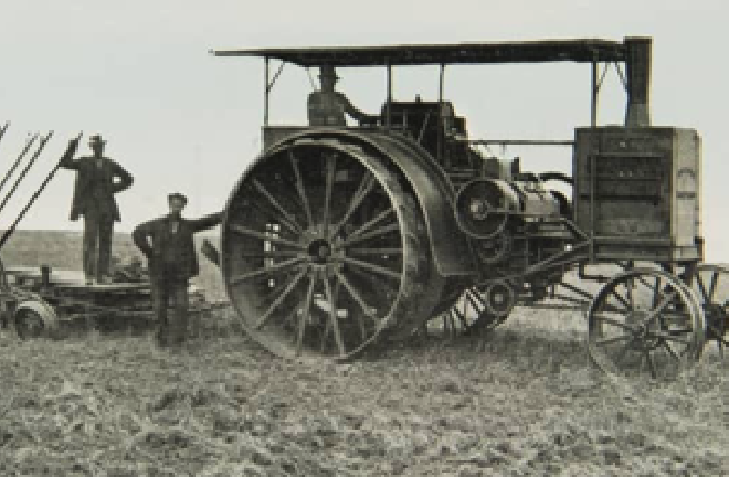 Three men are operating a steam engine with a plow and a harrow behind it.