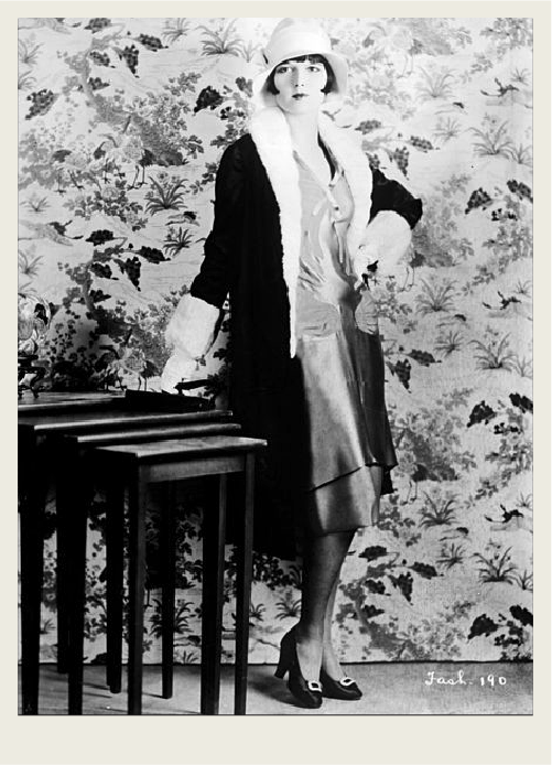 past-the great depression-the roaring 20s-02 A woman from the 1920s is standing for a photo, wearing short hair, a hat, a knee-length dress and high-heels.