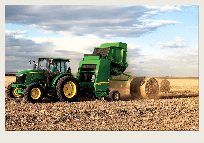 Photo caps-06 A green tractor is pulling a baler that is completing and kicking a bale out into the field.