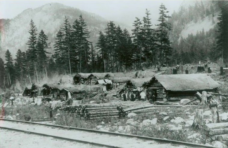 Approximately nine tiny shed-looking buildings are jammed together. These buildings are the living quarters for the Chinese men that were working on the railway.