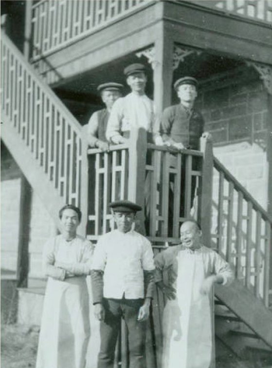 Six Chinese men stand together outside an apartment building where they are staying together.