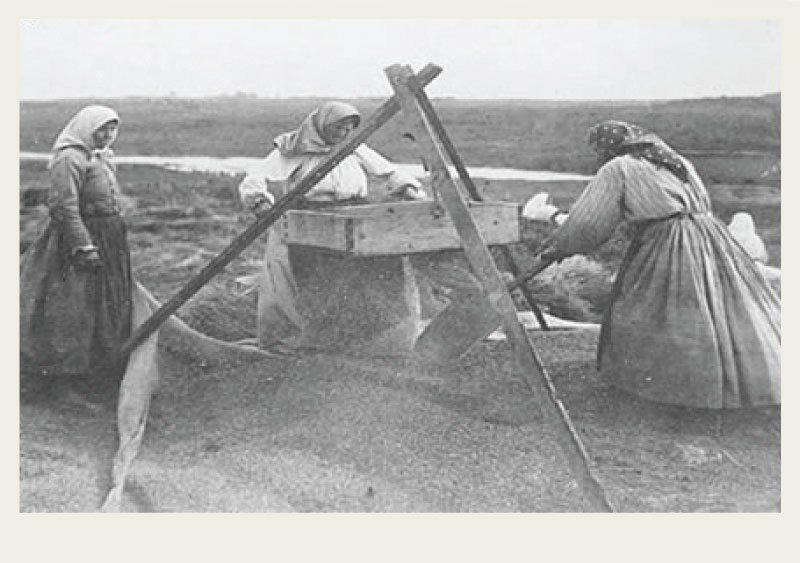 Past-Immigration-Doukhobours-Settlement-threewomen Three Doukhobor women are using a winnowing tray to separate grain from the rest of the stalk.
