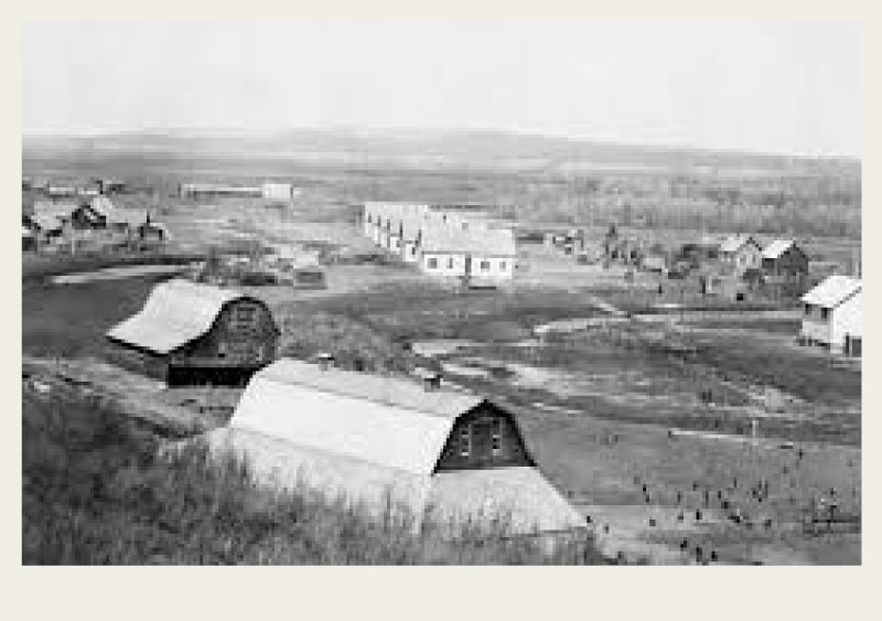 Three men are casually standing around outside of a log home.