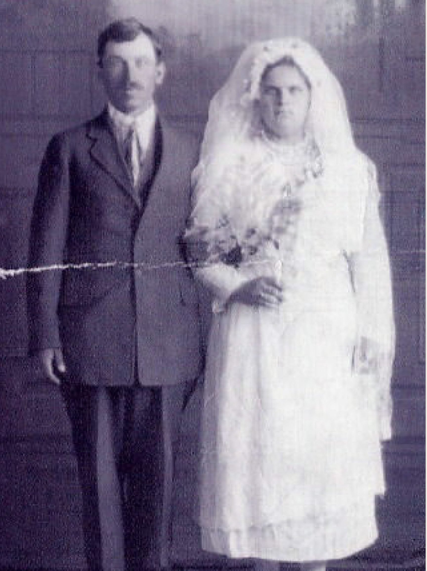 A man and woman are dressed up in their wedding outfits and posing for a wedding photo.