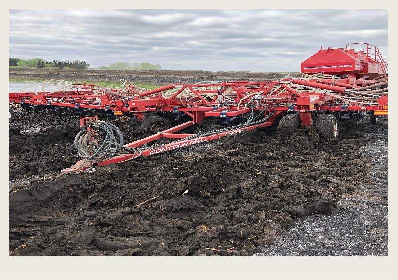 An air drill and tank are stuck in a field full of mud.