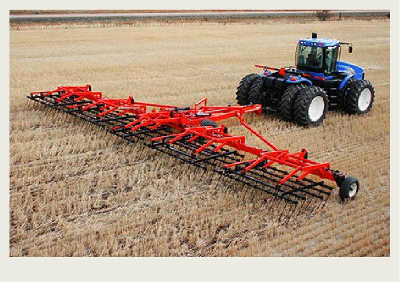 A tractor pulls harrows in a field.