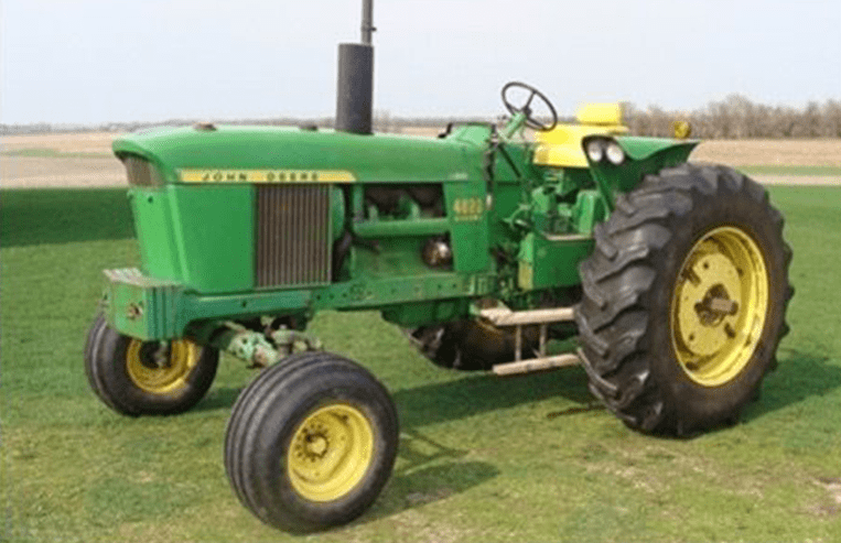 A JD 4020 tractor is parked in a farm field.