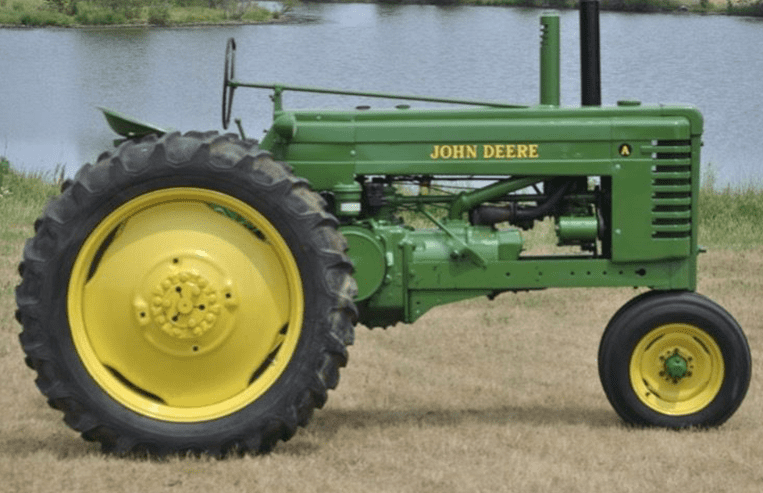A green and yellow open-cab tractor is parked in a field.