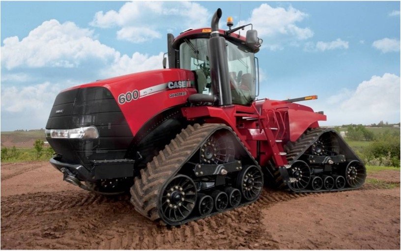 A red tractor with tracks is parked in a field.