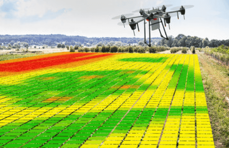 A drone flies above a crop that has a coloured map over it with red, yellow, and green areas highlighted.