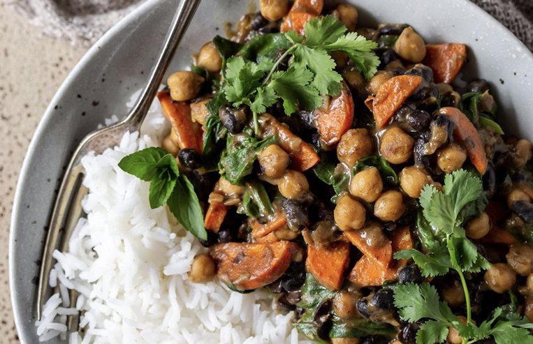 A plate sits on a counter full of rice and sauce made of chickpeas and vegetables.