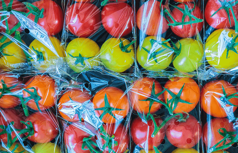 Tomatoes are grouped together in plastic bags sit ready to be sold.