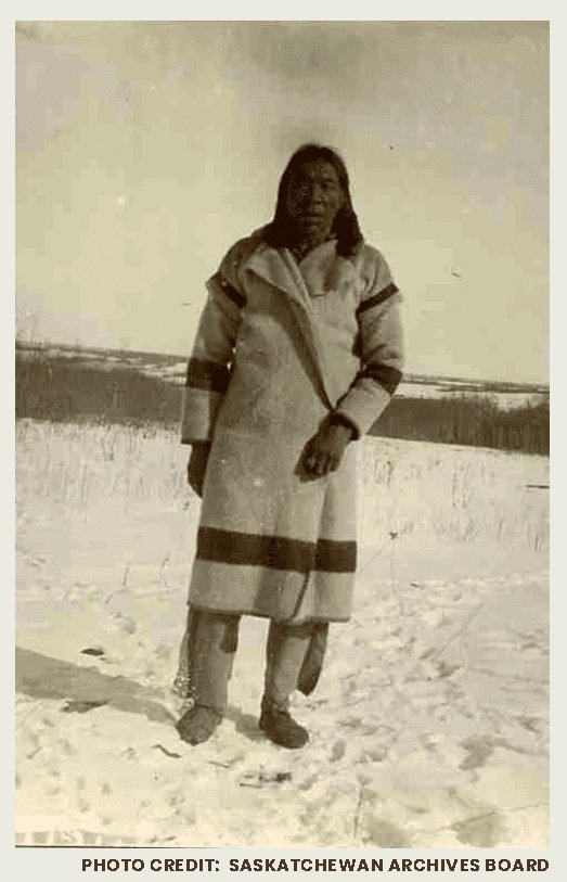 A First Nations man is photographed somewhere in the parkland of central Saskatchewan during winter. He is wearing Hudson's Bay Company clothing.