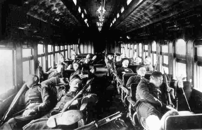 Image of troops holding weapons while in a train car enroute to action in the Northwest Resistance is shown.