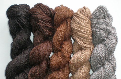 Five bundles of llama yarn are piled next to each other.