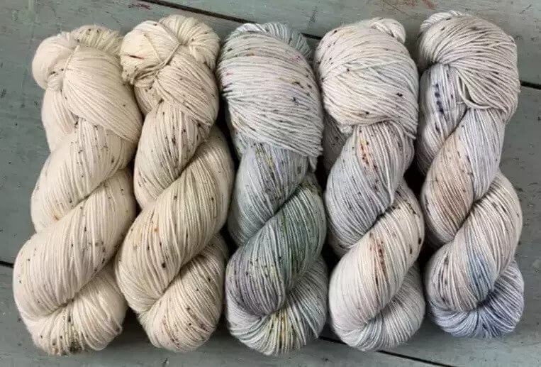 A roll of white llama fibre sits on a wooden surface.