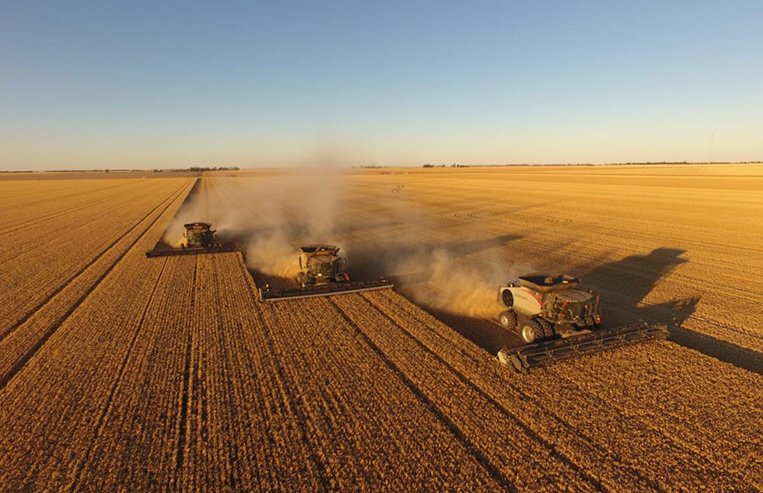 A train is stopped in a small town next to a train station and two elevators.