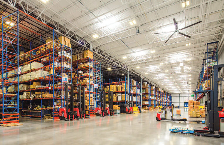 The inside of a large food distribution centre has many rows of food on shelves.
