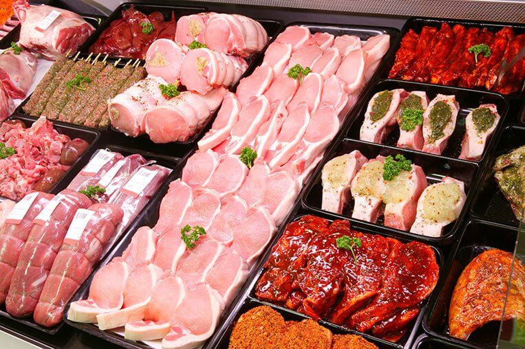 Different types of meat cuts are shown in the meat aisle of a grocery store.