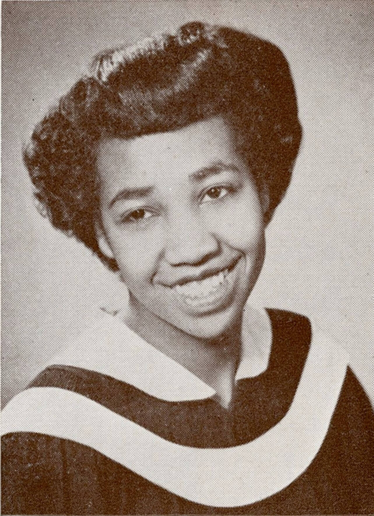 A man plays a harmonica while wearing a 1920s hat and suit.