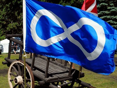 A piece of art by Leah Marie Dorion made with mosaics shows two Indigenous people standing near animals, sun, and water.